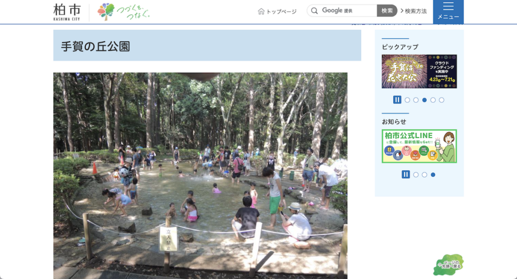 柏市ホームページの手賀の丘公園のページ。森林の中の涼しげなじゃぶじゃぶ池の中で多くの人が涼を取っている。