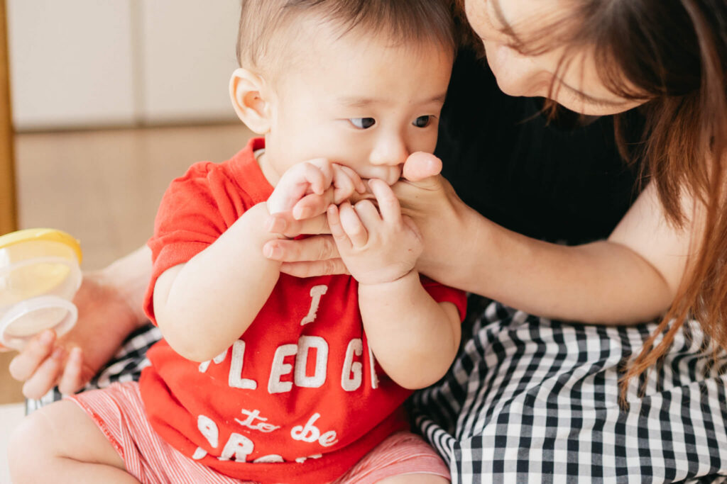 柏・流山｜母の手に触れながらおやつを口にする赤ちゃんの自然な仕草を捉えた日常写真