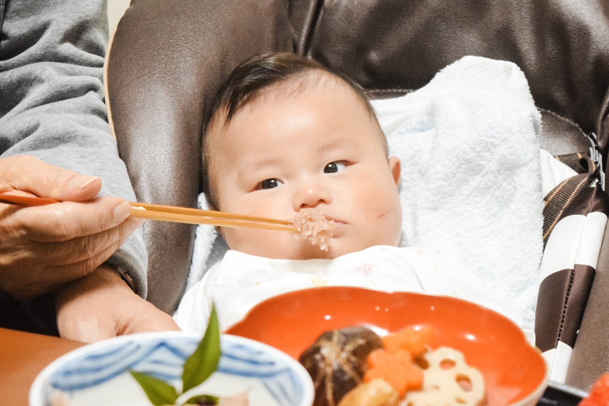 自宅でのお食い初めで赤ちゃんにご飯を食べさせている様子