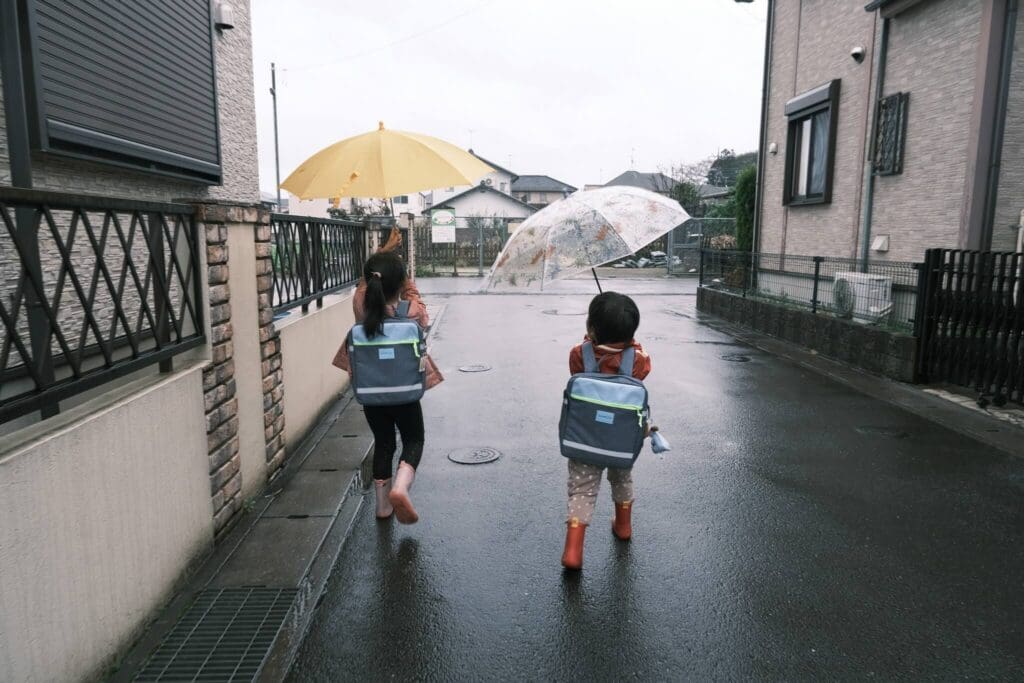 雨の日の住宅街を歩く子どもたち