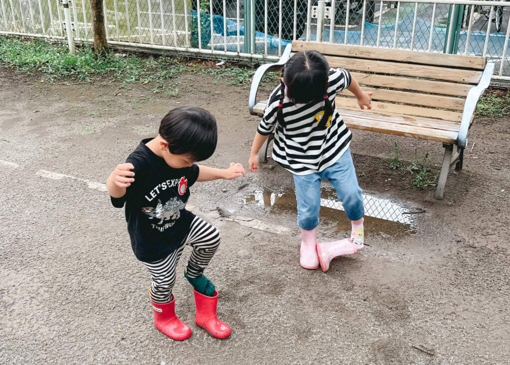 雨上がりの公園で水たまり遊びをする子どもたち