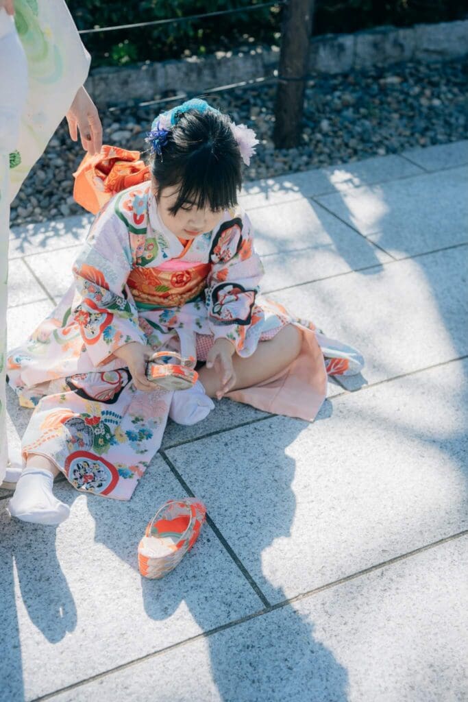 七五三の途中で座り込み、草履を脱いで休憩する女の子