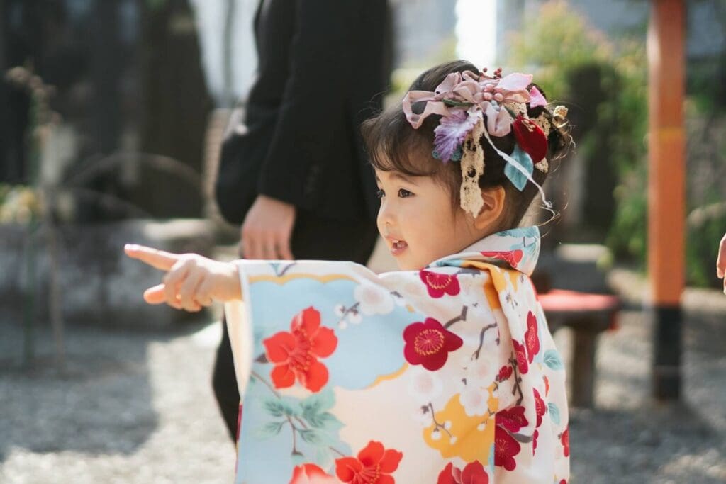 神社の境内で指をさして話す着物姿の女の子