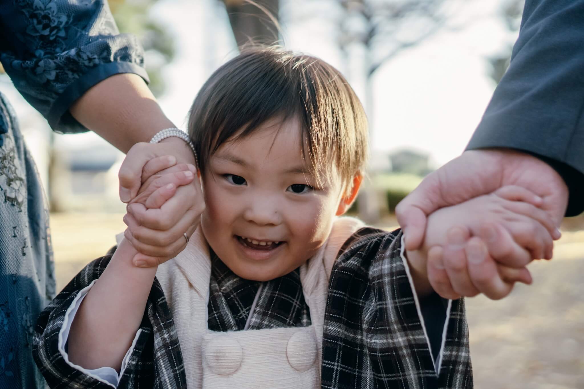 被布を着て両親と手を繋ぐ3歳男の子の七五三の様子
